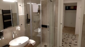 A modern bathroom with a glass-enclosed shower, a white sink, and a mirror. - Confortevole ed Ampio Appartamento in Alghero a Ridosso del Parco Tarragona (Alghero)