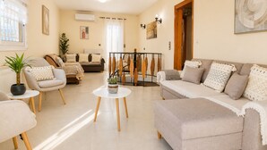 Uma sala de estar com sofá, cadeiras, mesa de centro e um espaço para refeições.