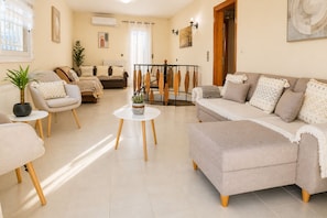 A living room with a sofa, chairs, a coffee table, and a dining area.
