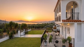 A two-story building with a balcony overlooking a scenic view of the sea and mountains at sunset. - Villa Aelia Luxury Maisonette (ΑΙΑΝΤΕΙΟ ΣΑΛΑΜΙΝΑ)