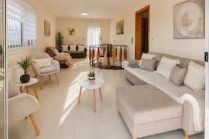 Un salon comprenant un canapé, des fauteuils, une table basse et un coin repas avec une table ronde.