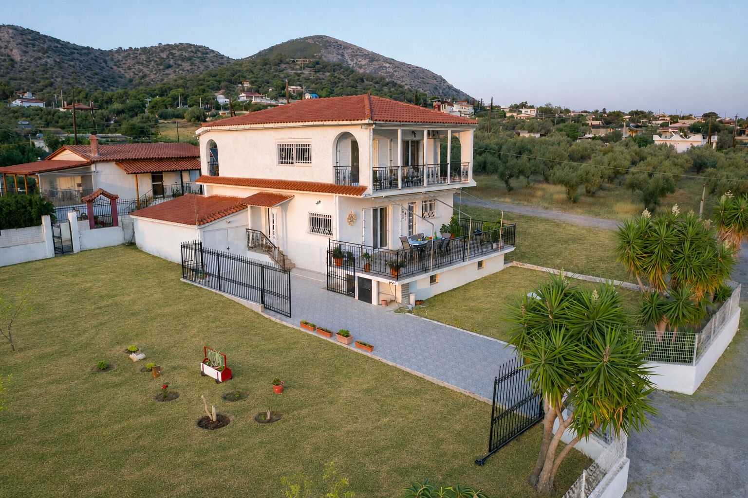 A two-story house with a balcony, surrounded by a well-maintained lawn and palm trees.