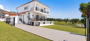 Un bâtiment blanc à deux étages, doté d’un balcon, d’une allée pavée et d’une pelouse bien entretenue.