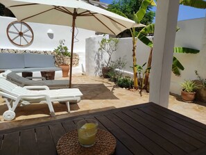 A sunlit patio with lounge chairs, a table with a drink, and potted plants. - La Morera is a 7-minute walk from Portet Beach in Moraira. (Moraira)