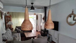 Un saló modern amb un sofà, una taula de centre i llums penjants. Hi ha una televisió penjada a la paret i una llar de foc.