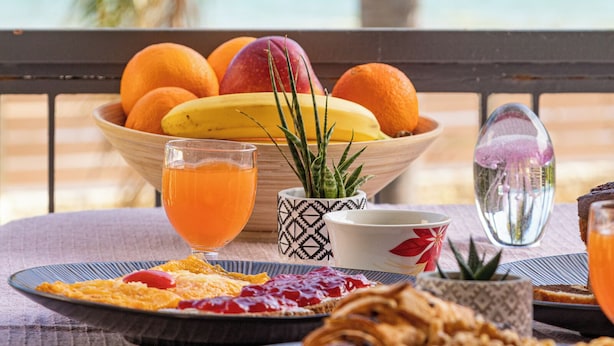 A breakfast table with fruits, a glass of orange juice, and a view of the ocean. - 4-bedroom villa in lovely Mili with AC, WiFi. Enjoy a relaxing stay (MILI)