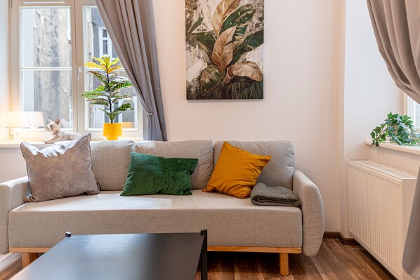 A living room with a sofa, a coffee table, a potted plant, and a painting on the wall. - RentPlanet - plac Uniwersytecki (Wroclaw)