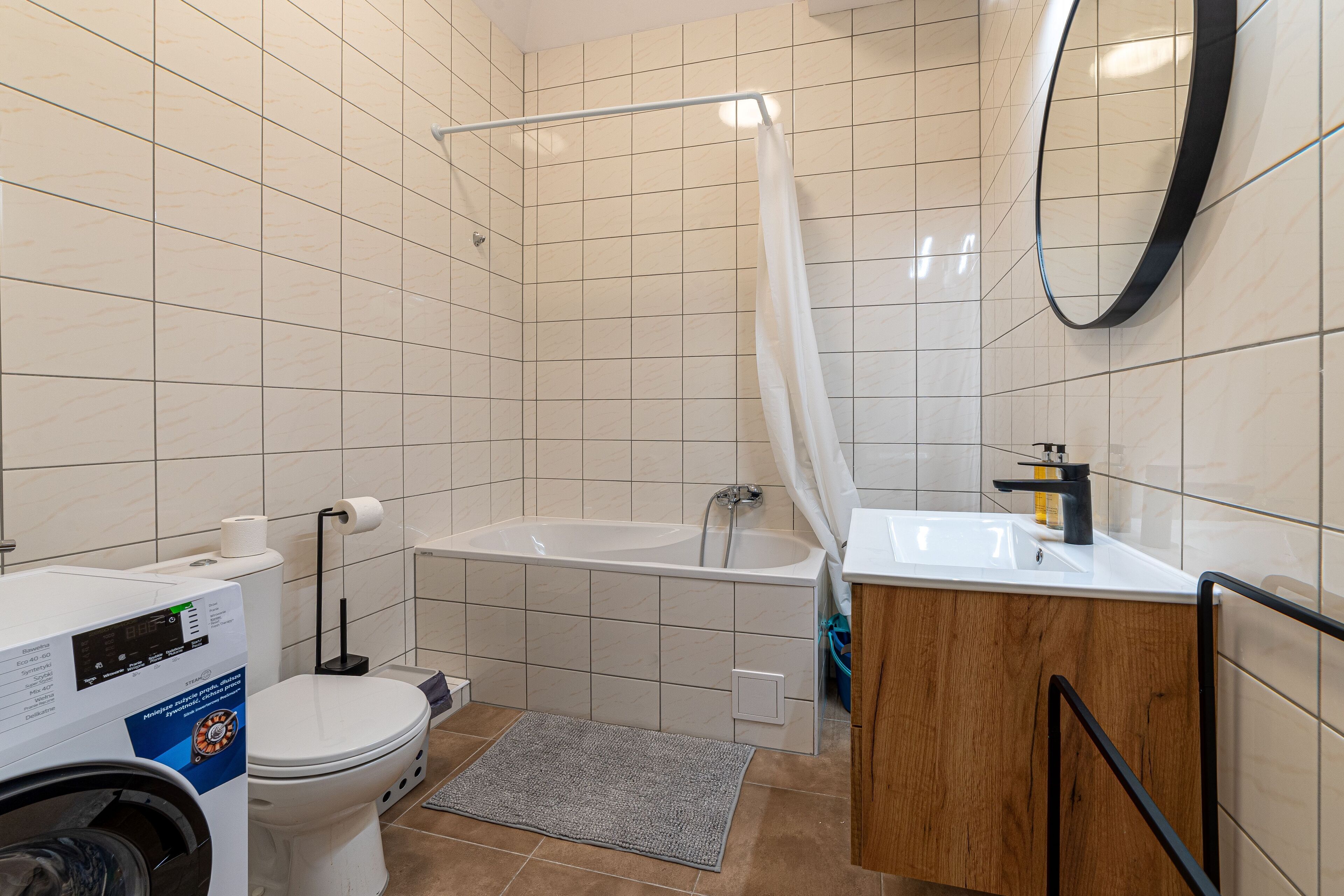 A bathroom with a bathtub, toilet, washing machine, and a sink.