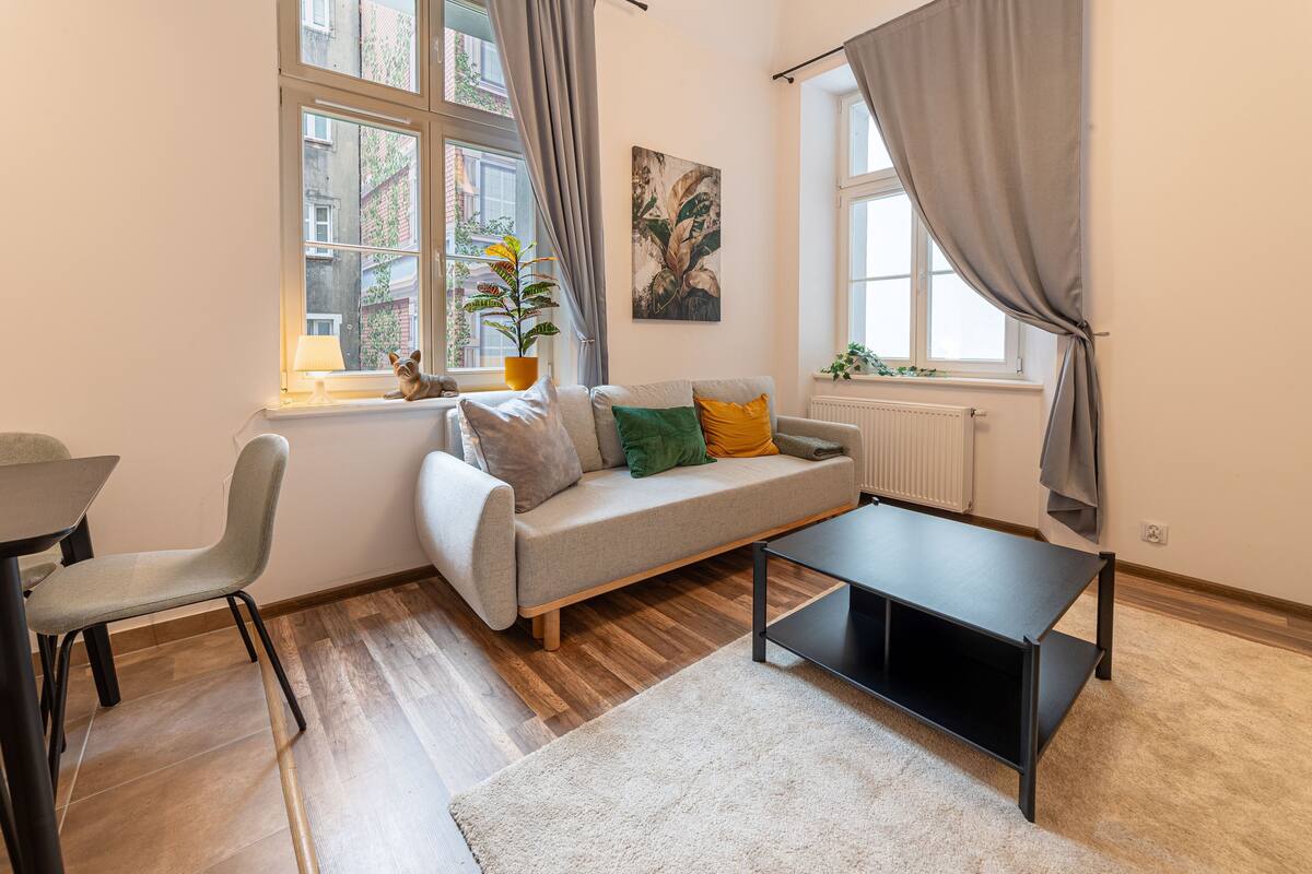 A living room with a sofa, a coffee table, a chair, and a potted plant.
