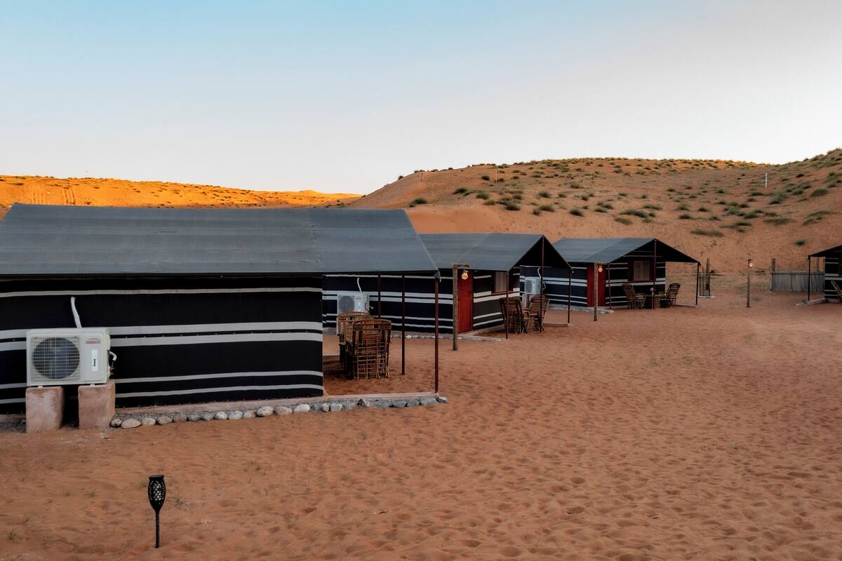A desert camp with several cabins, each with a small porch and outdoor seating.