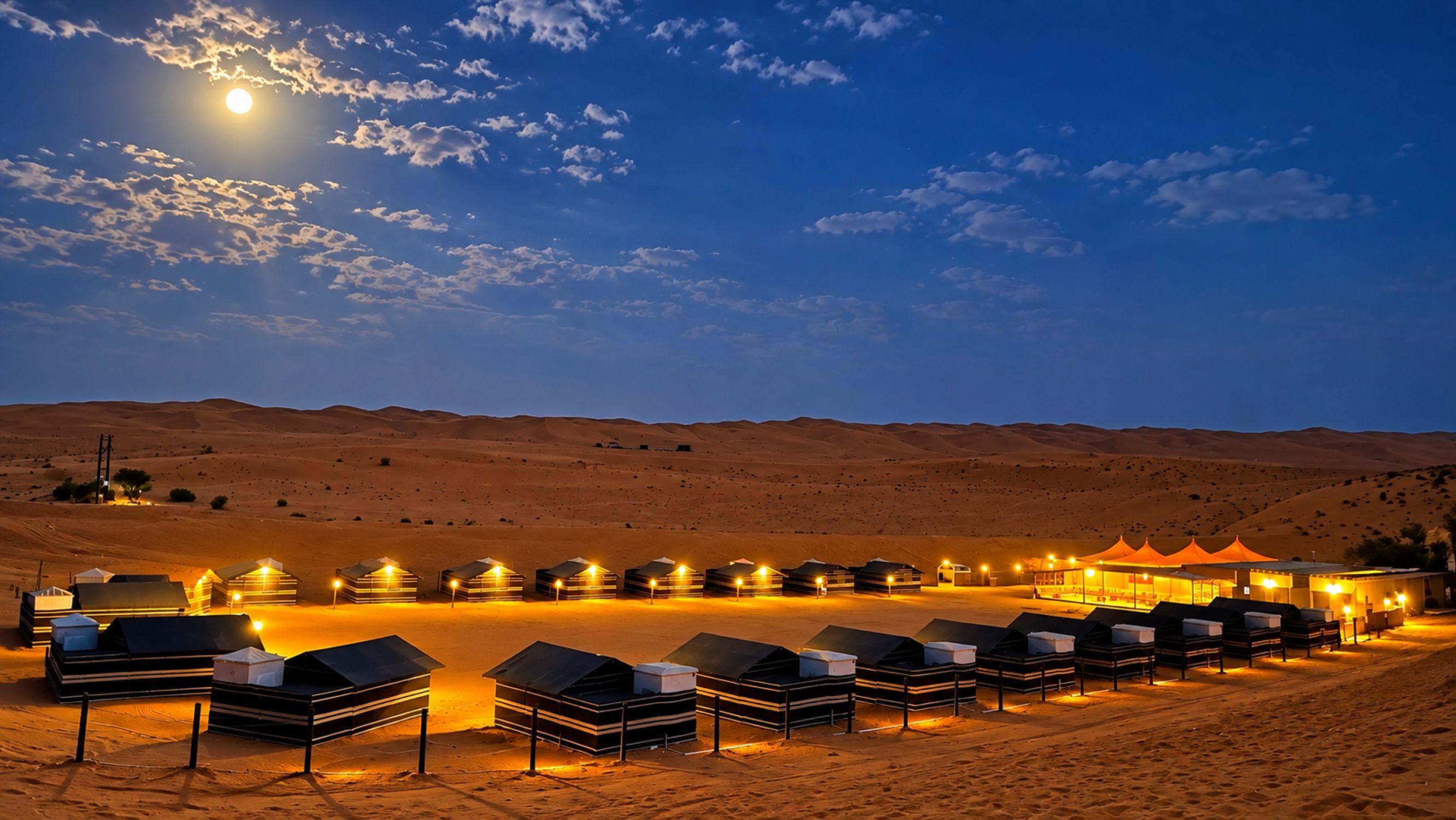 A desert campsite with tents and a central building at dusk.