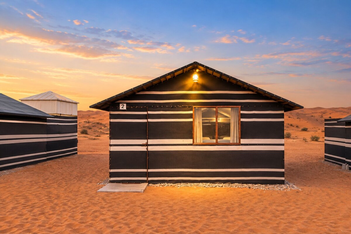 A single-roomed, striped, desert-style building with a visible number '2' on the side, a door, and a small window.