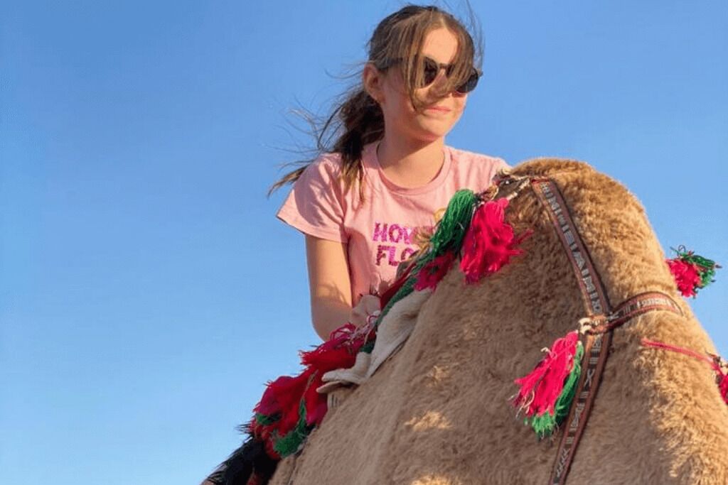 A person riding a camel with decorative tassels.