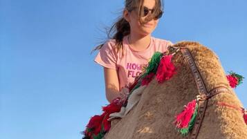 A person riding a camel with decorative tassels.