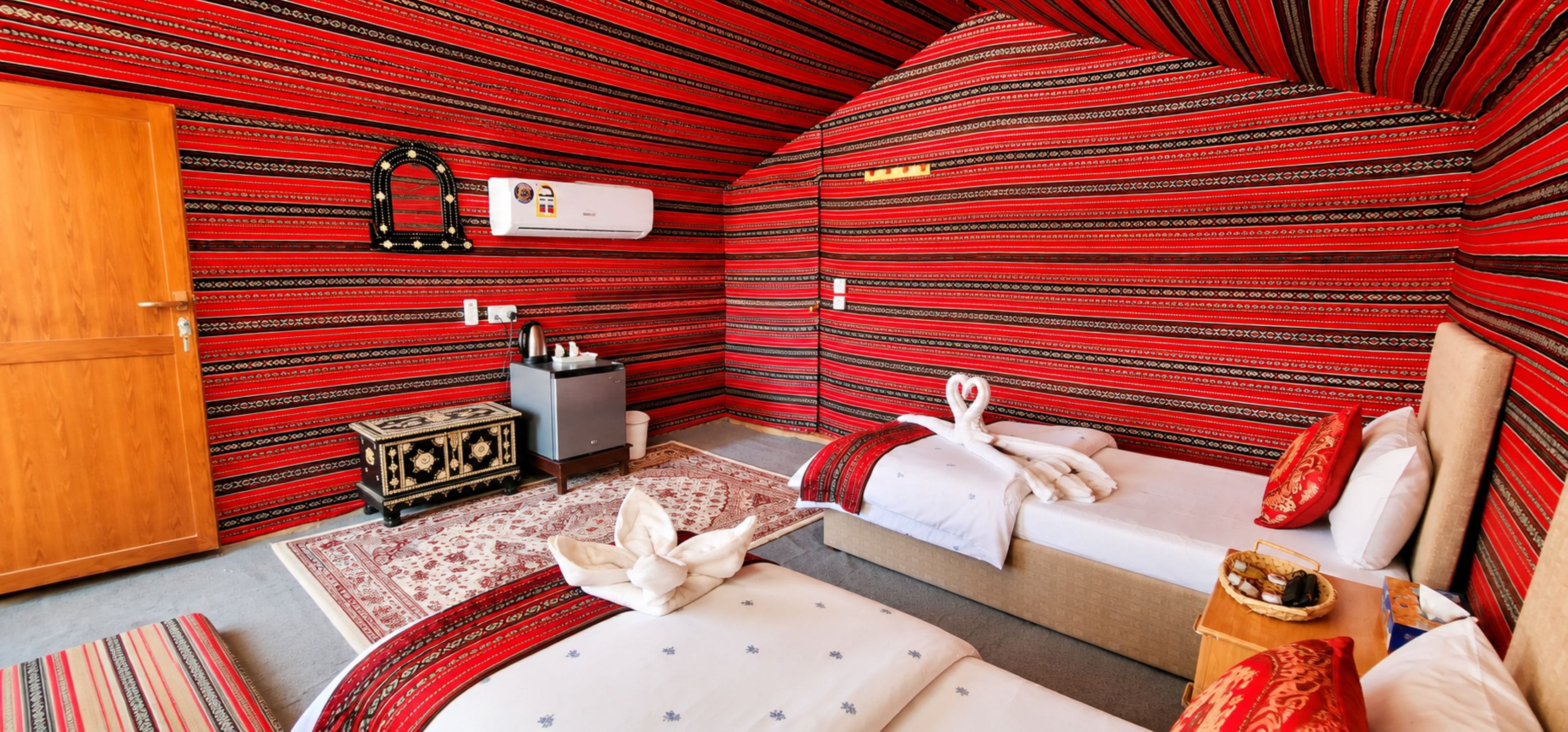 A compact room with a bed, a small table, a wardrobe, and a heater on the wall.