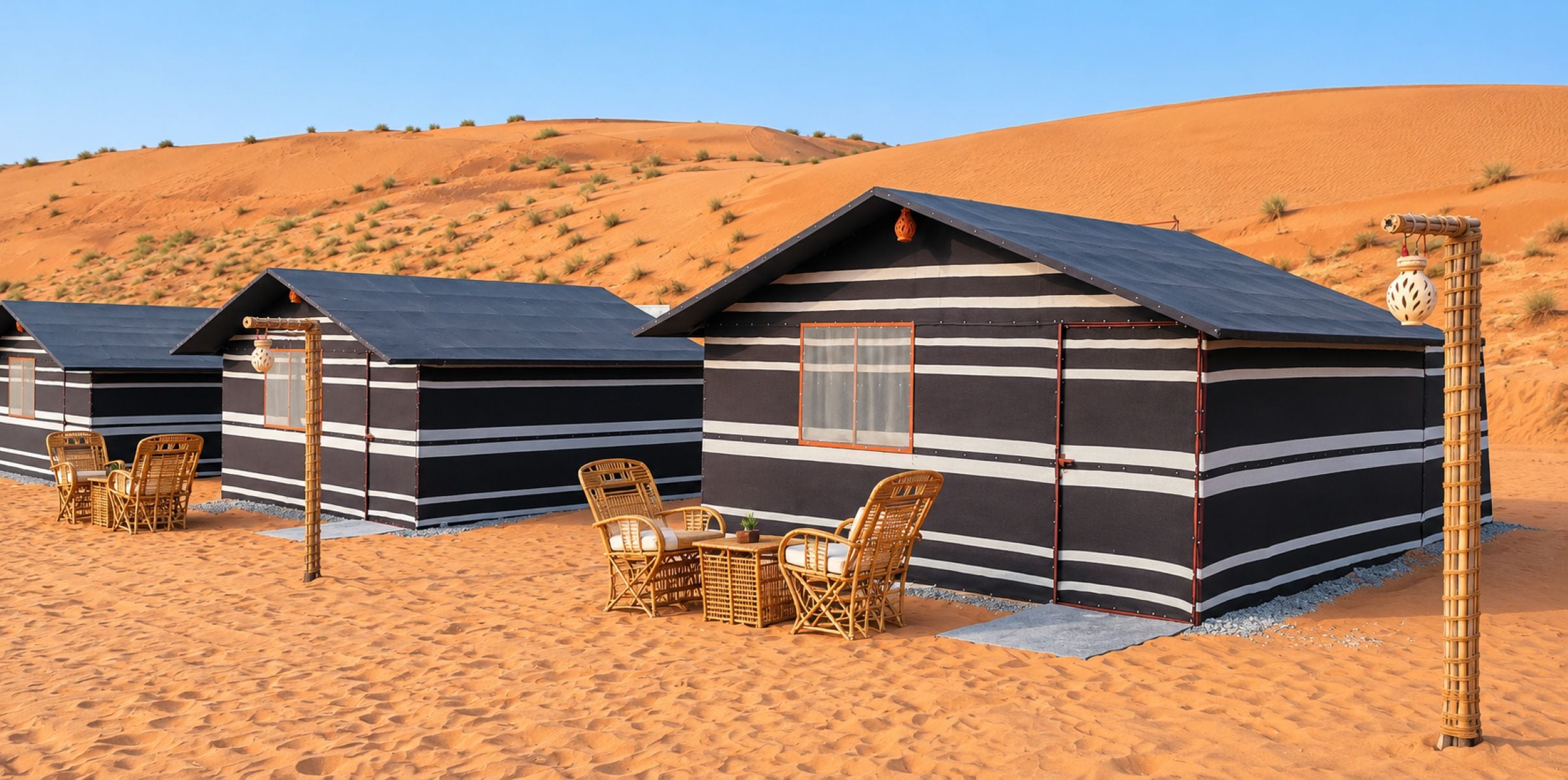 Eine Reihe von gestreiften, eingeschossigen Wüstencabins mit Sitzgelegenheiten im Freien.