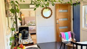 A kitchen with a dining area, a coffee machine, a fruit bowl, and a hanging plant.