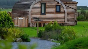 Eine Holzhütte mit gewölbtem Dach, einem kleinen Fenster und einer Holztür.