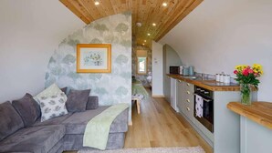Ein gemütliches Wohnzimmer mit Sofa, einem kleinen Tisch und einer Küchenzeile mit Mikrowelle und Spüle.