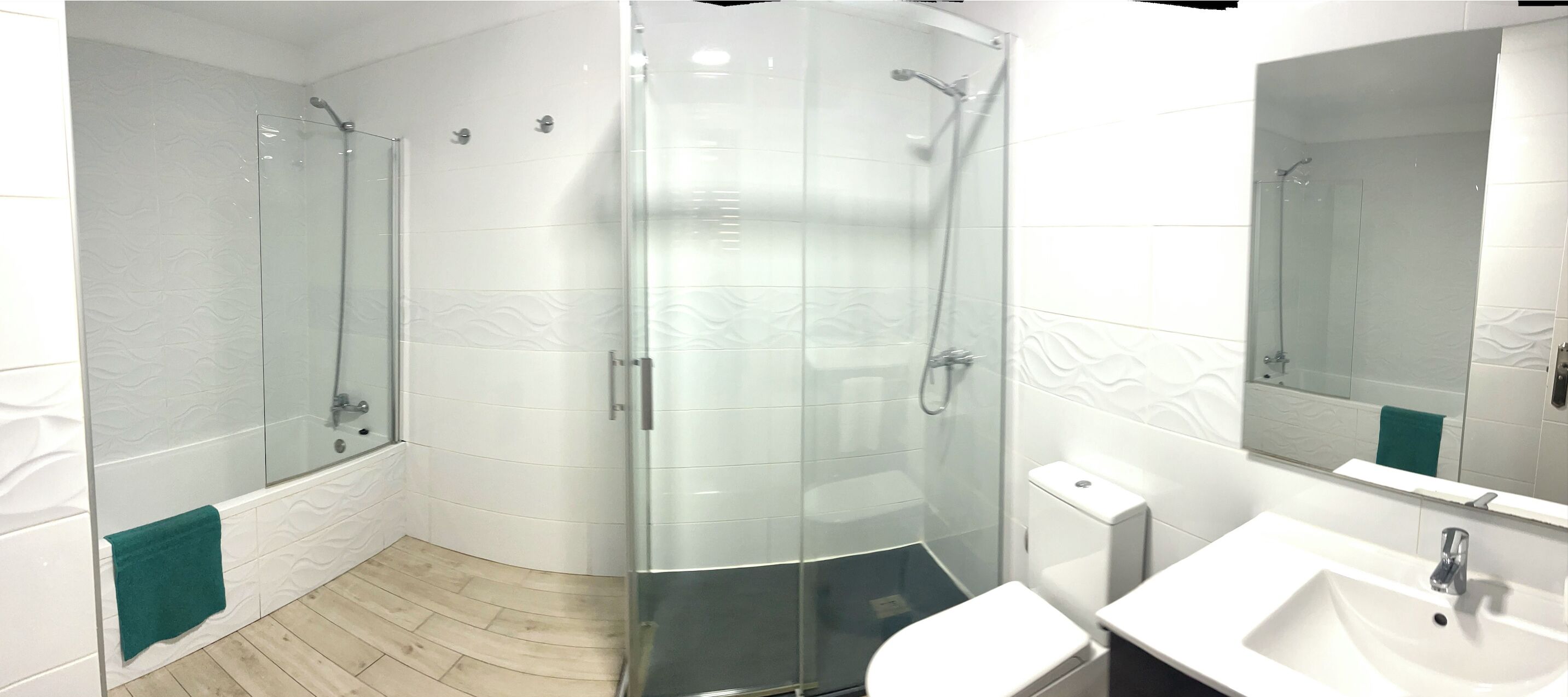 Un baño moderno con ducha acristalada, un lavamanos blanco y un espejo.