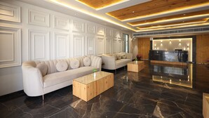 A modern lobby with a sofa, a coffee table, and a reception desk. - The Maasai Mara Resort Water and Adventure Park Corbett (Ramnagar)
