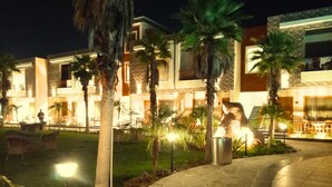 A hotel with a courtyard, palm trees, and a stone pathway. - The Maasai Mara Resort Water and Adventure Park Corbett (Ramnagar)