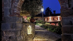 Una escalera de piedra arqueada que conduce a un edificio con tejado de baldosas, rodeado de follaje y un farol.