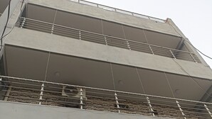 A multi-story building with a flat facade, balconies, and a patterned wall.