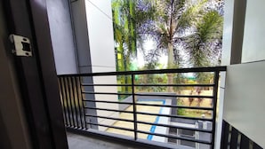 A view through a metal gate into a courtyard with a pool, surrounded by greenery and palm trees. - Ecoland 88 Apartelle and Suite near SM Davao (Davao)