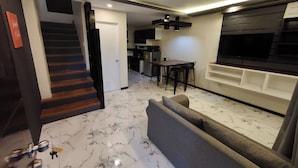 A modern living room with a marble floor, a sofa, a dining table, and a kitchen area with a microwave and refrigerator. - Ecoland 88 Apartelle and Suite near SM Davao (Davao)