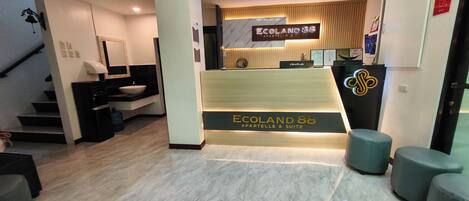 A reception area with a reception desk, a sign for 'Ecoland 88', and a staircase leading to another floor.