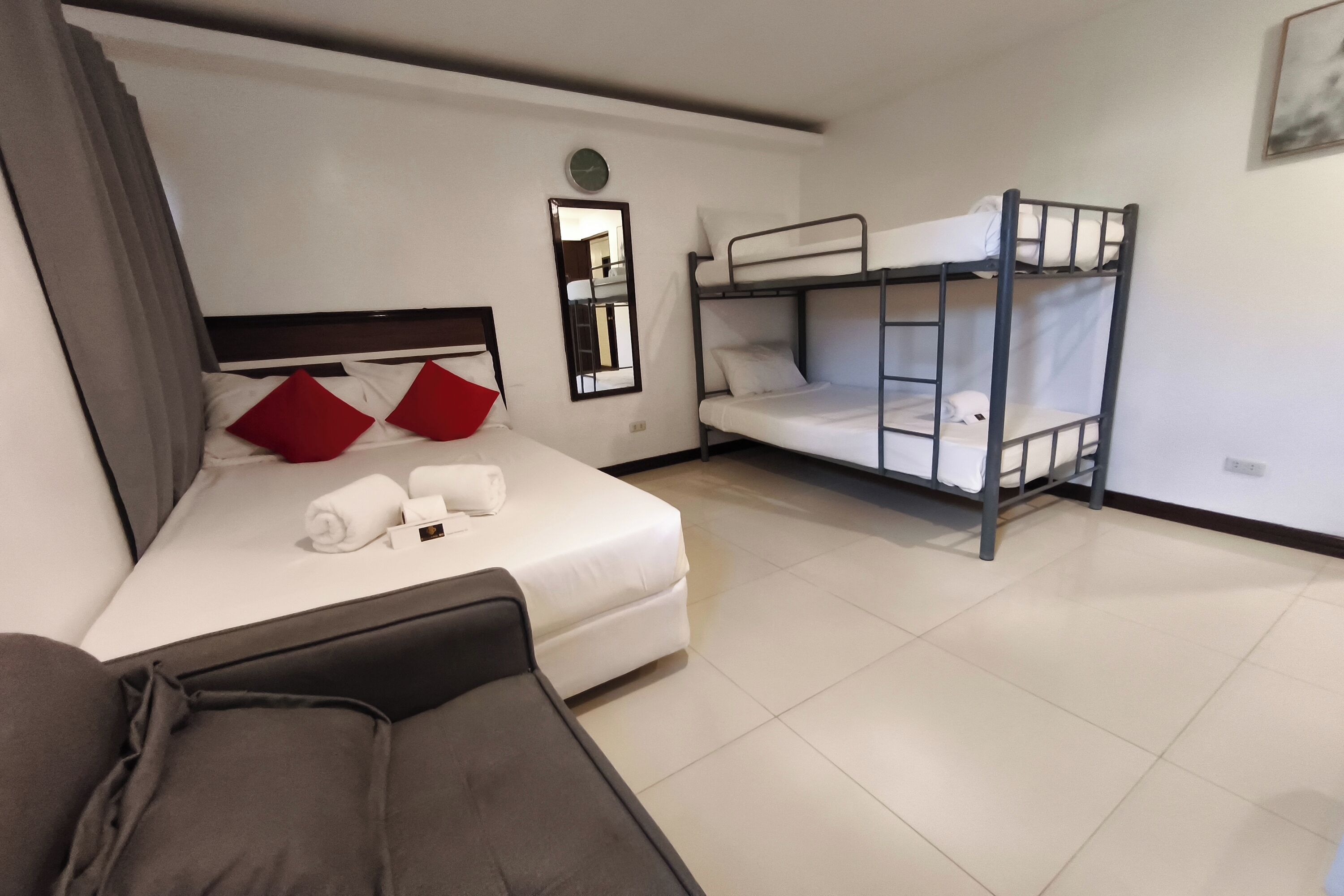 A hotel room with a bed, a couch, and a bunk bed.