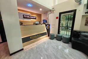 A reception area with a wooden reception desk labeled "Ecoland 88 Apartelle & Suite" and a black leather sofa. - Ecoland 88 Apartelle and Suite near SM Davao (Davao)