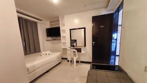 A hotel room with a bed, a desk, a chair, a TV, and a door with a number. - Ecoland 88 Apartelle and Suite near SM Davao (Davao)