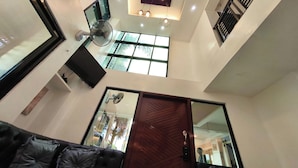 A modern living room with a dark-colored sofa, a wooden door, and a large window. - Ecoland 88 Apartelle and Suite near SM Davao (Davao)