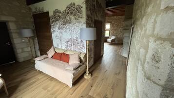 Ein gemütliches Zimmer mit Holzboden, einem Bett mit beiger und roter Bettdecke und einer Wandmalerei von Bäumen.