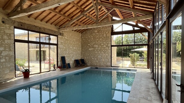Una piscina interior con paredes de piedra y vigas de madera.