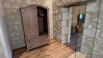 Una habitación con un armario de madera, una puerta de cristal y una pared de piedra.