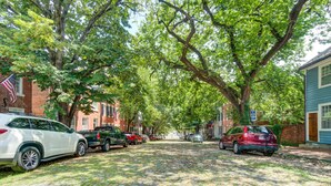 A cobblestone street lined with parked cars and trees. - HEART of Old Town! Historic 1BR! 99 Walk Score! (Alexandria)