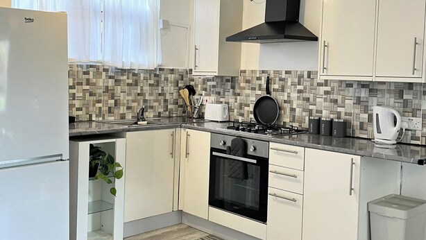 Una cocina moderna con refrigerador, horno, estufa y gabinetes blancos.