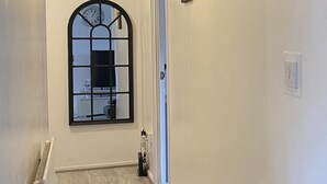 Un pasillo con un amplio ventanal de arco, un radiador y un enchufe en la pared.