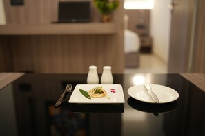 A dining table with a plate of food, a fork, and a knife. There are two salt shakers on the table.
