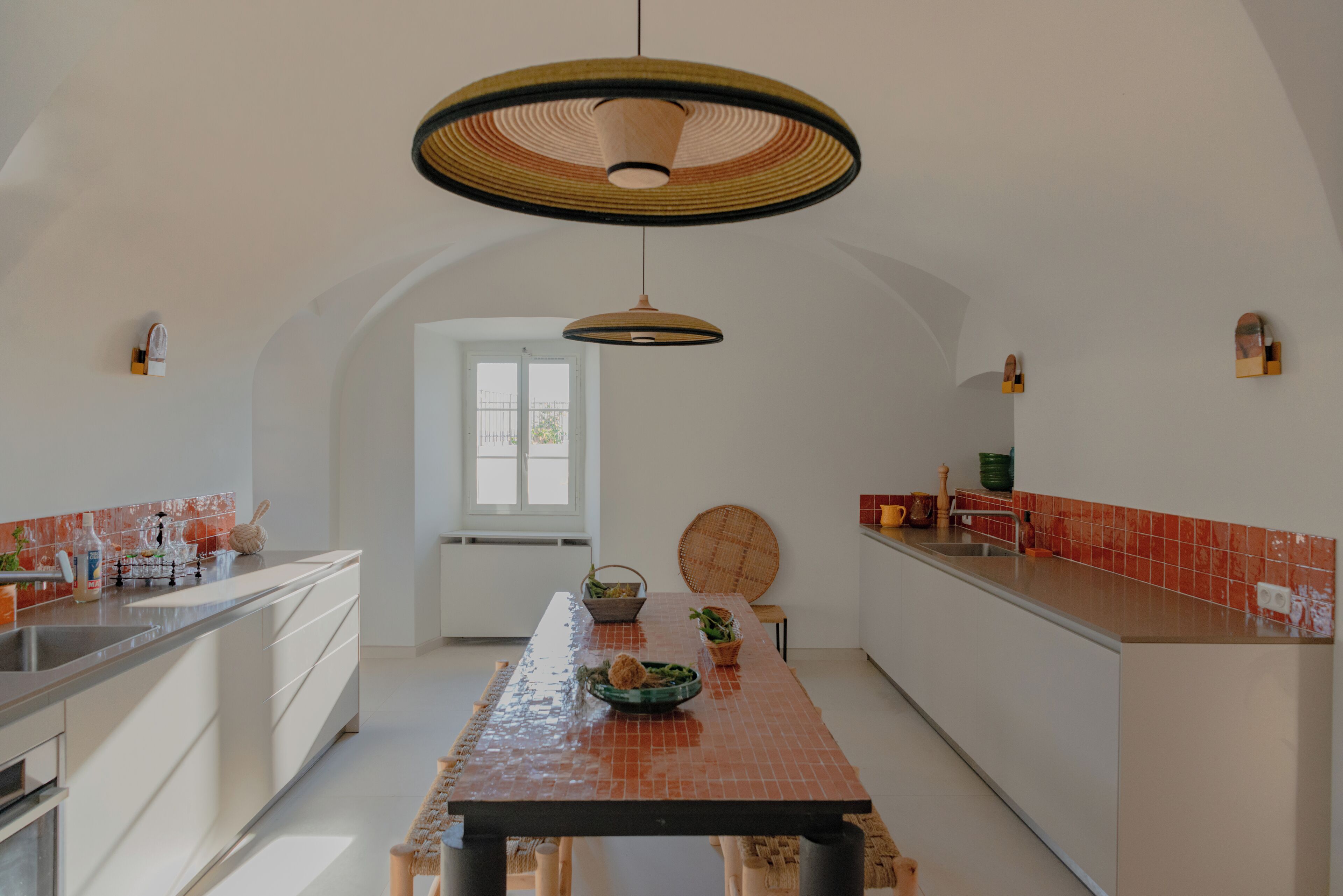 A modern kitchen with a central island, pendant lighting, and a view to the dining area.