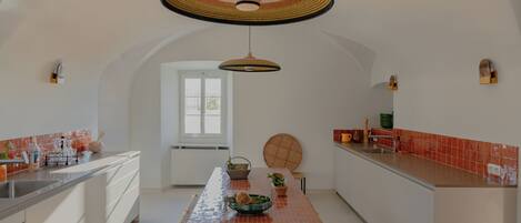 A modern kitchen with a central island, pendant lighting, and a view to the dining area.