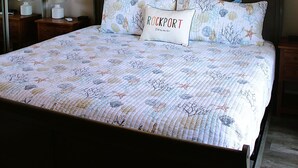 A bedroom with a bed, a ceiling fan, a wall-mounted fish decoration, and a nightstand with a lamp. - Third floor view overlooking canal (Rockport)