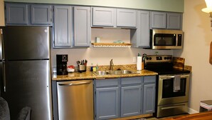 A kitchen with a refrigerator, dishwasher, microwave, stove, and granite countertop. - Third floor view overlooking canal (Rockport)