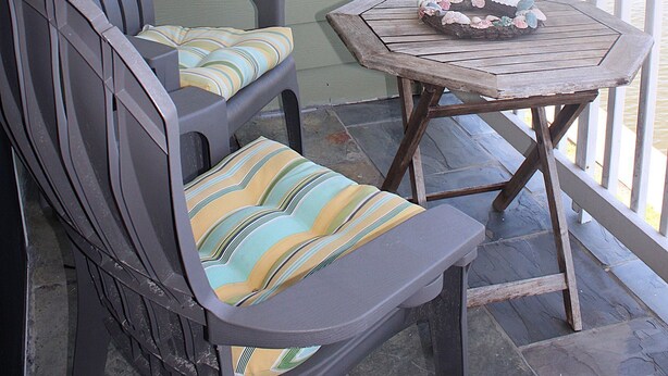 A porch with a gray Adirondack chair and a small wooden table with a cushion. - Third floor view overlooking canal (Rockport)