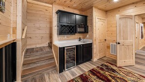Ein Holzinterieur mit Küchenbereich, inklusive Mikrowelle, Spüle und schwarzen Schränken.