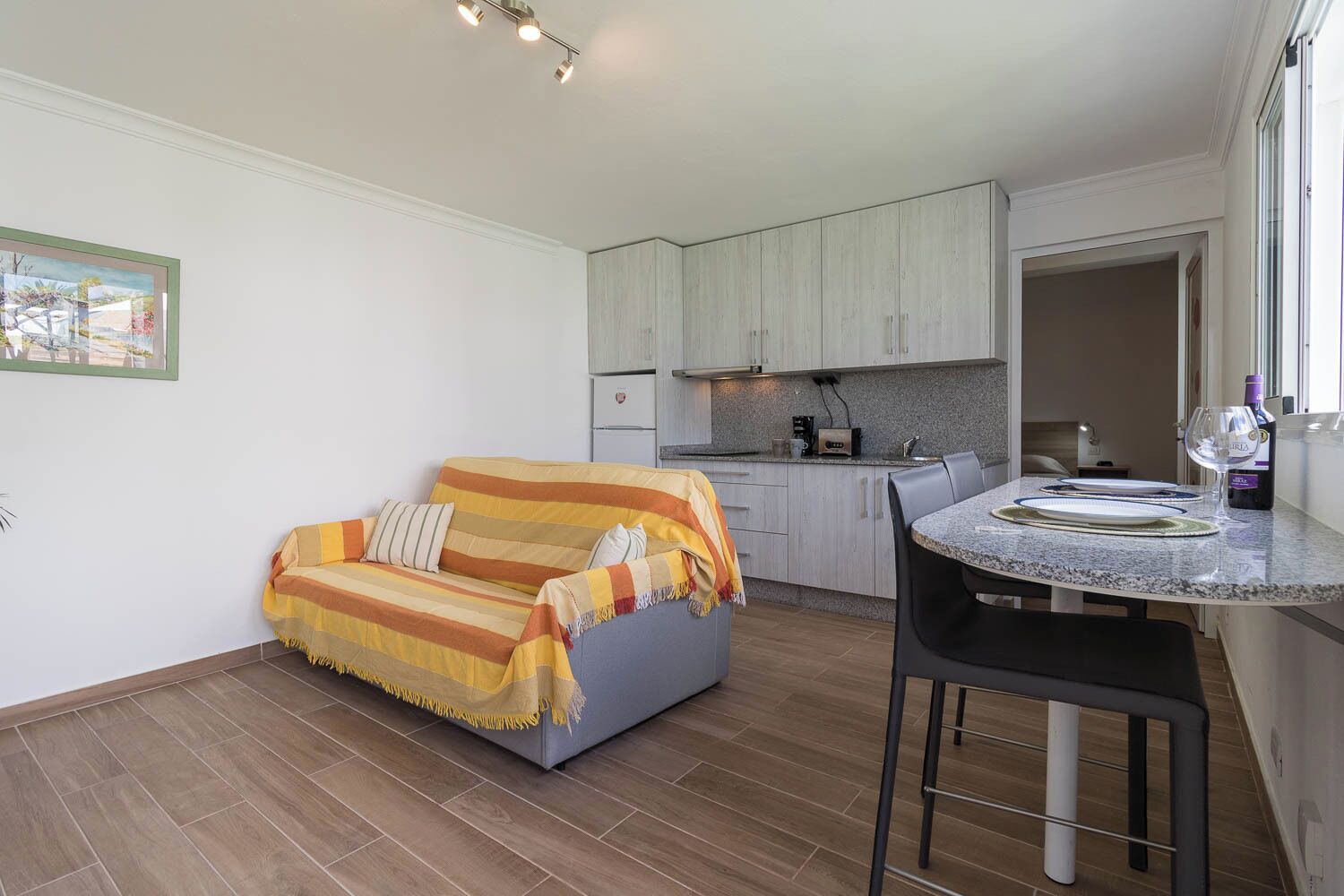 A compact living space with a sofa, a dining table, and a kitchenette.