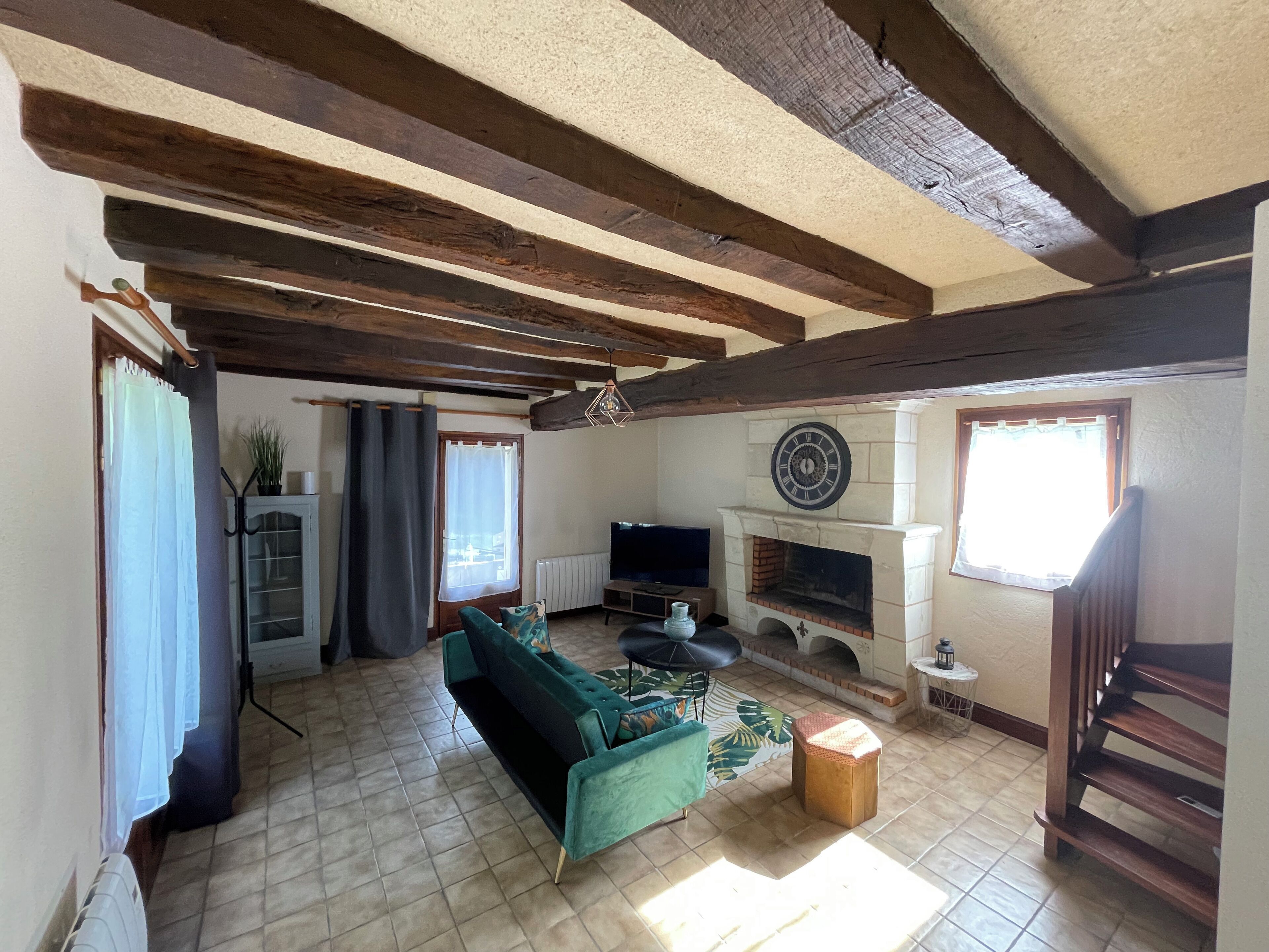 Una sala de estar con chimenea, un sofá, un televisor y una escalera.